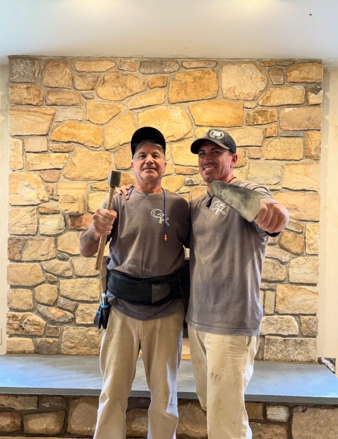 Luciano and Alex Sansalone in front of a stone wall they built