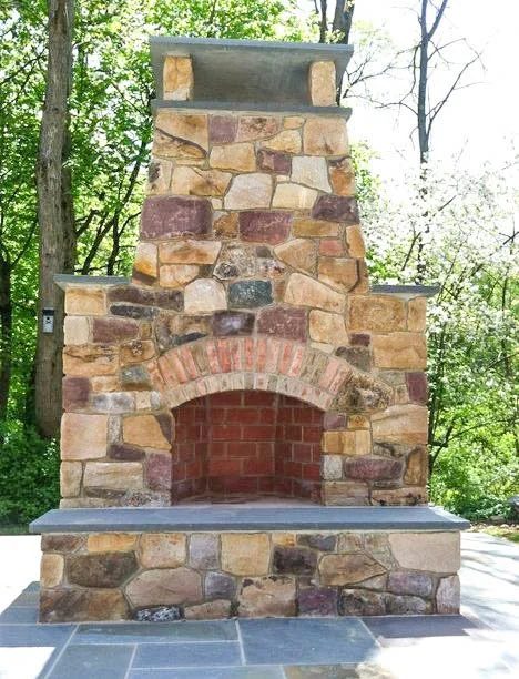 Outdoor real-stone fireplace with a brick arch and bluestone hearth