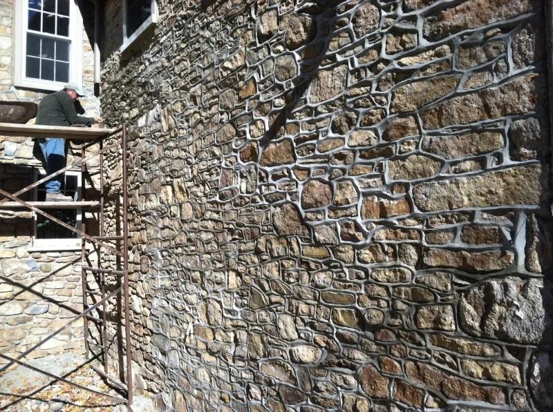 Fieldstone wall being repointed from scaffolding