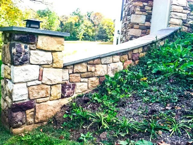 Fieldstone pillar tied into a capped wall